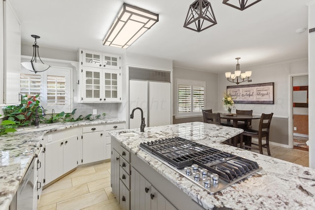 kitchen with a chandelier, stainless steel gas cooktop, paneled built in refrigerator, hanging light fixtures, and backsplash