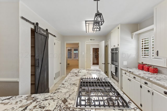 kitchen with pendant lighting, white cabinetry, a barn door, stainless steel appliances, and visible vents
