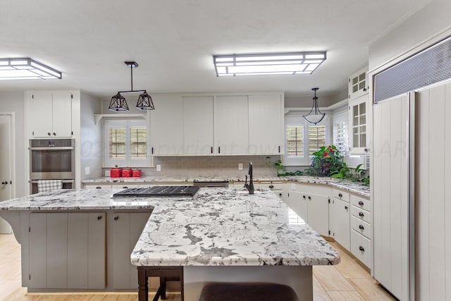 kitchen with tasteful backsplash, stainless steel appliances, hanging light fixtures, a kitchen island, and white cabinets