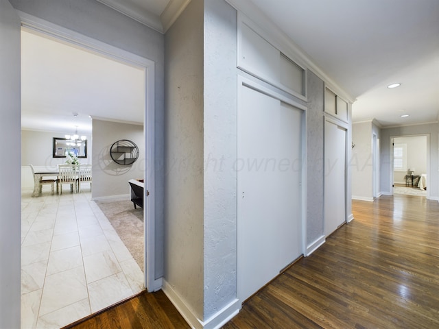 corridor with a chandelier, wood finished floors, baseboards, ornamental molding, and recessed lighting
