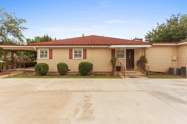 view of front of house with an attached carport, driveway, and central AC