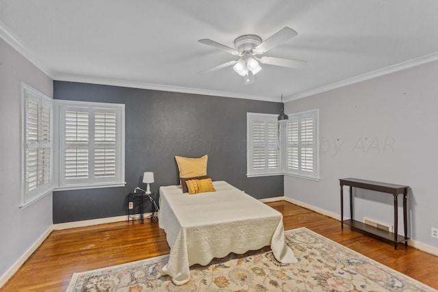 living area with baseboards, wood finished floors, ornamental molding, and a ceiling fan