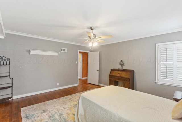bedroom with a ceiling fan, wood finished floors, baseboards, visible vents, and ornamental molding