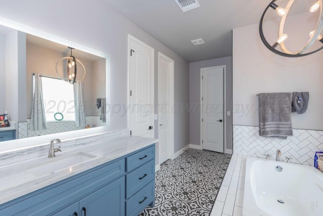 bathroom with a relaxing tiled tub, vanity, and tile patterned flooring