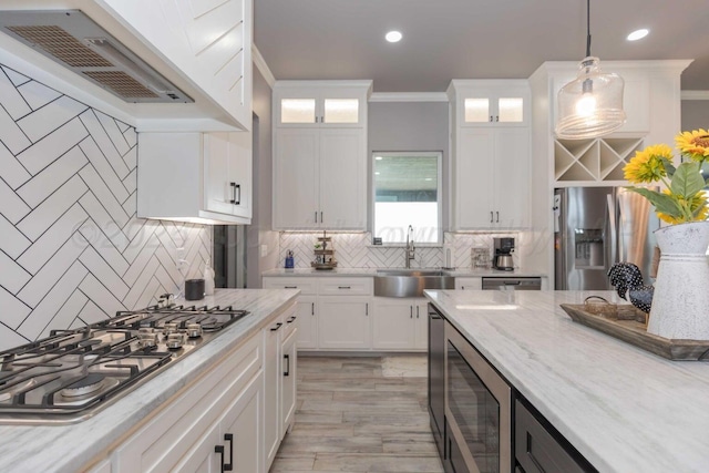 kitchen with pendant lighting, custom exhaust hood, sink, white cabinetry, and stainless steel appliances