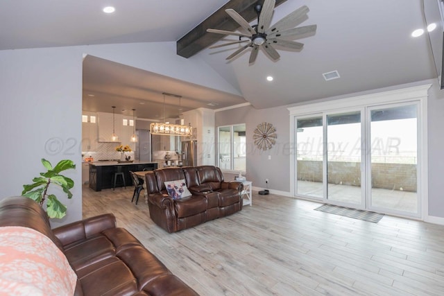 living room featuring ceiling fan with notable chandelier, light hardwood / wood-style flooring, and lofted ceiling with beams