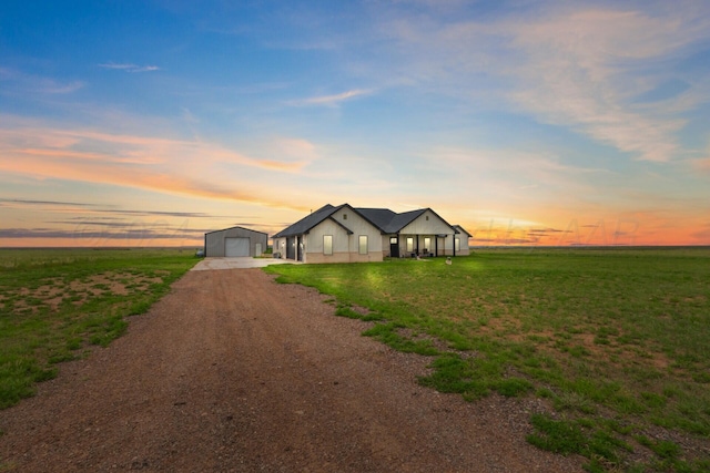 view of front facade with a lawn, a rural view, and a garage