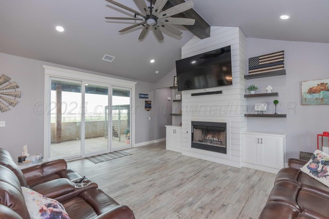 living room with ceiling fan, a large fireplace, light hardwood / wood-style flooring, and lofted ceiling with beams