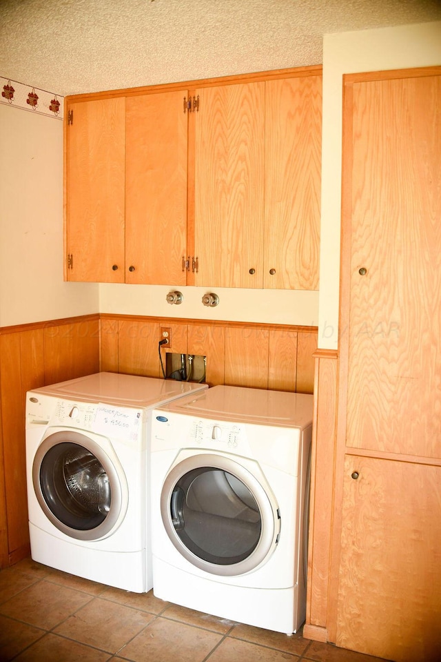 laundry room with washer and clothes dryer, cabinets, wooden walls, and tile patterned floors