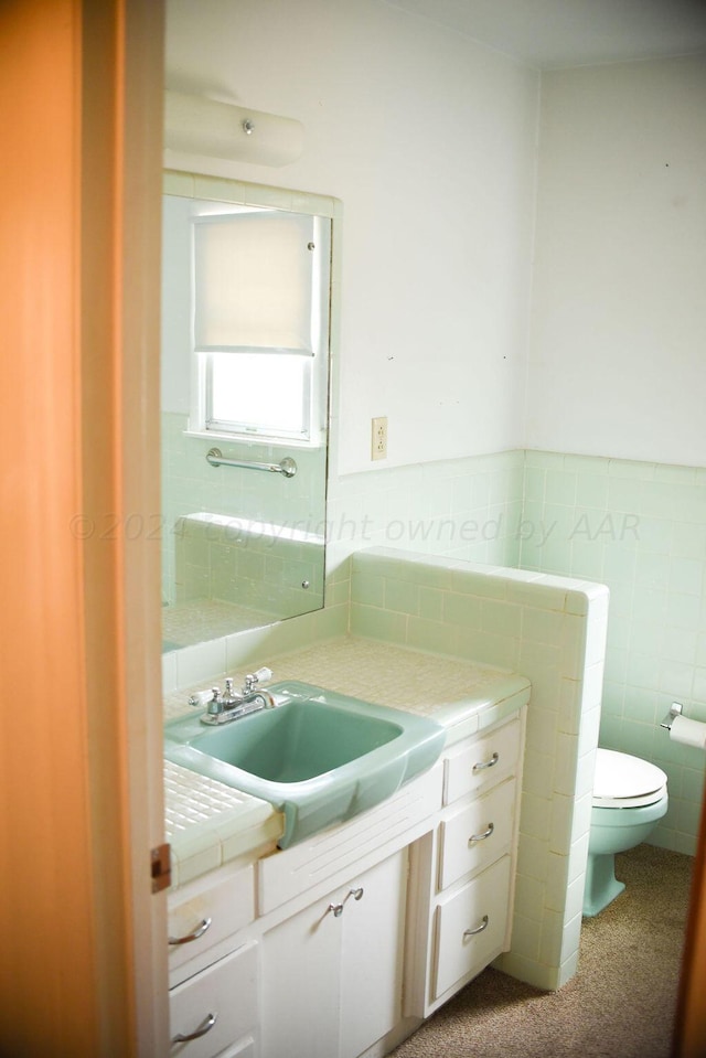 bathroom with toilet, vanity, and tile walls