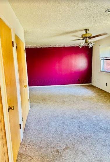 unfurnished room with a textured ceiling, carpet flooring, and ceiling fan