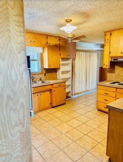 kitchen with sink, ceiling fan, a textured ceiling, light tile patterned floors, and exhaust hood