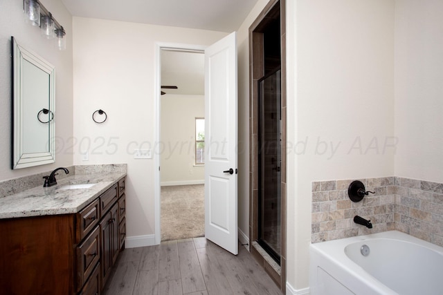 9407 Kori Dr, Amarillo, TX 79119 - bathroom featuring wood finished floors, vanity, baseboards, a stall shower, and a garden tub