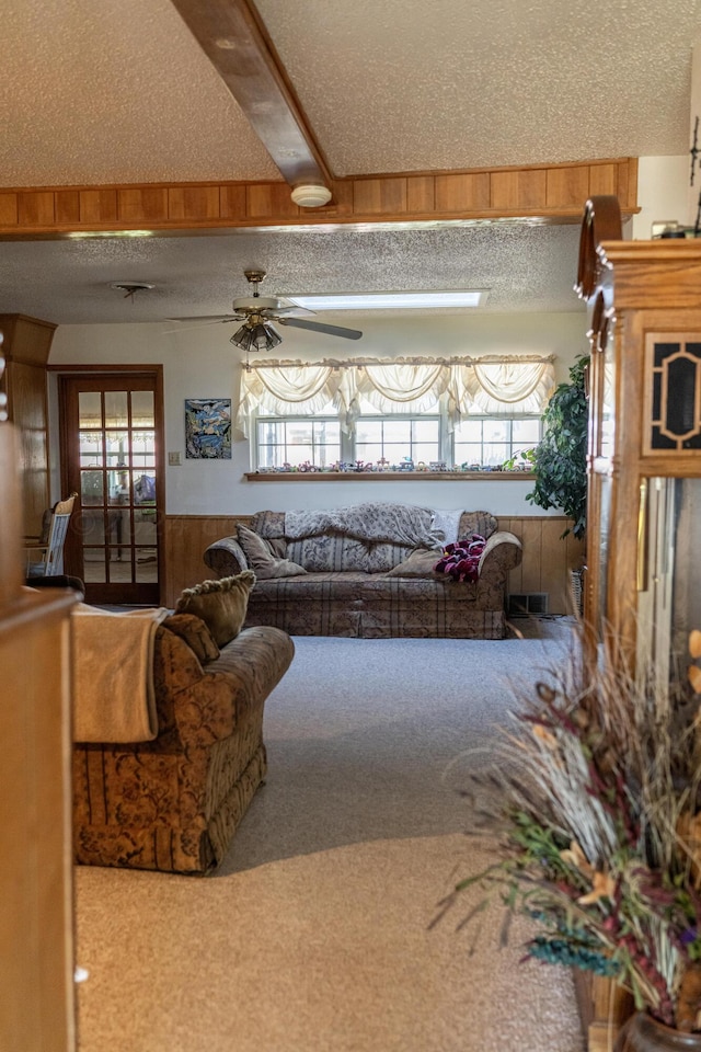 carpeted living room with a wealth of natural light, a textured ceiling, and wooden walls