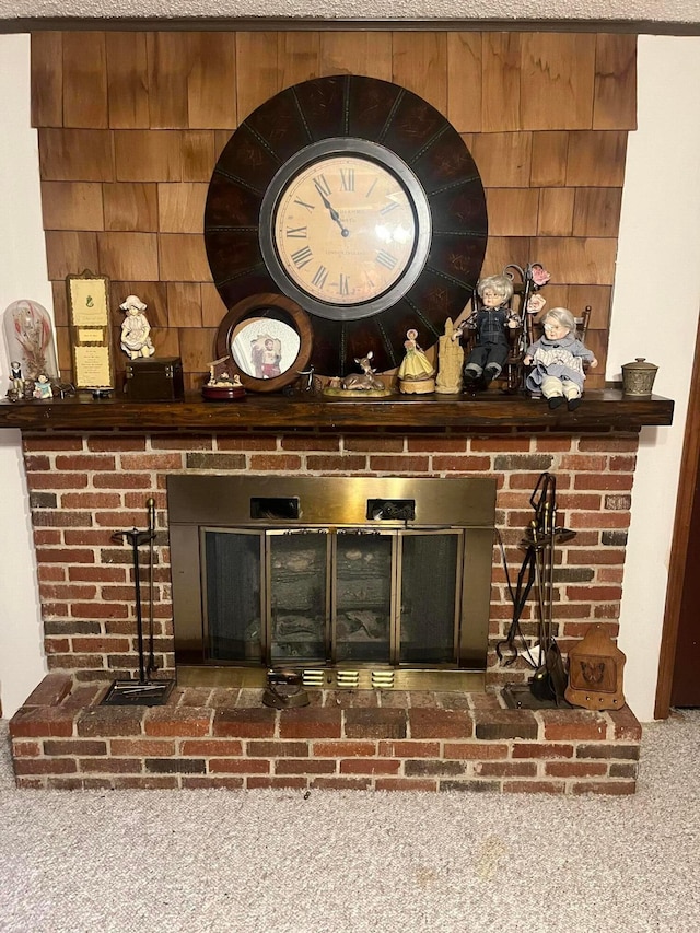 room details featuring a brick fireplace, a textured ceiling, wooden walls, and carpet floors