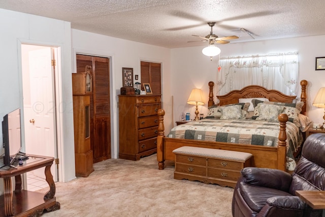 carpeted bedroom featuring a textured ceiling, ceiling fan, and two closets