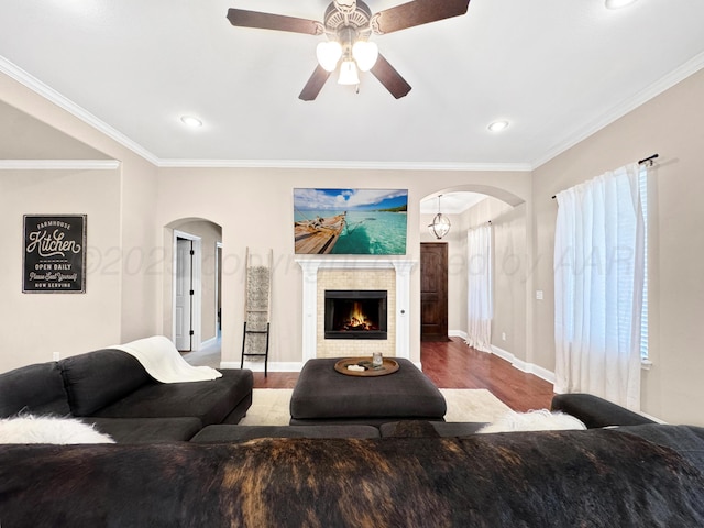living room with crown molding, arched walkways, baseboards, and wood finished floors