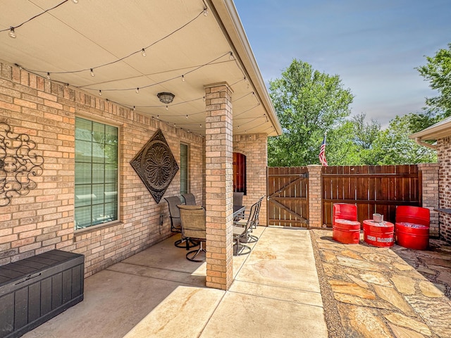 view of patio featuring fence, a gate, and outdoor dining area
