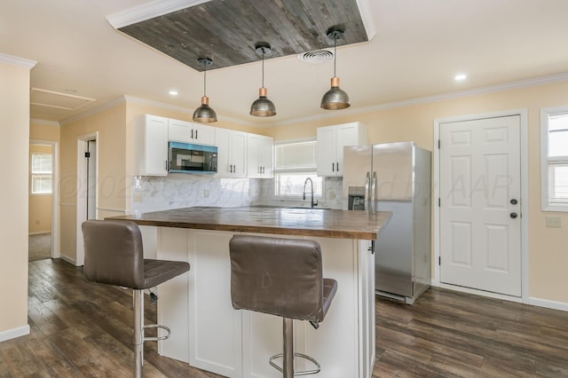 kitchen with white cabinetry, sink, a kitchen breakfast bar, wooden counters, and stainless steel fridge