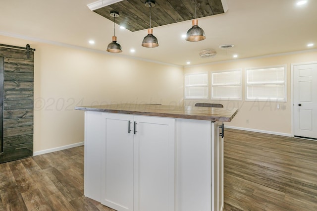 kitchen featuring white cabinets, a barn door, hanging light fixtures, and dark wood-type flooring