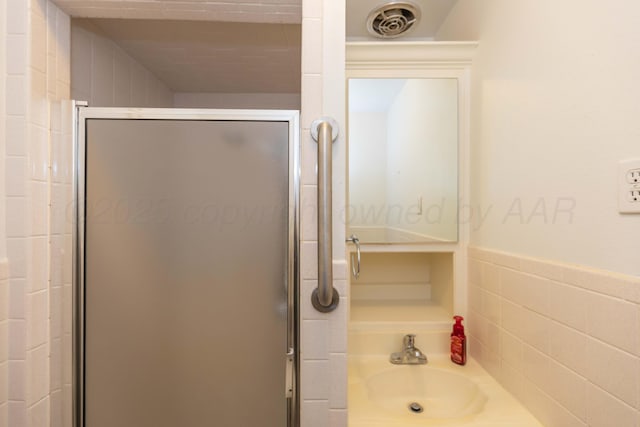 bathroom featuring a sink, a shower stall, and visible vents