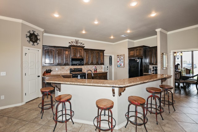 18150 19th St, Amarillo, TX 79124 - kitchen with black appliances, a kitchen breakfast bar, light tile patterned floors, tasteful backsplash, and dark brown cabinets
