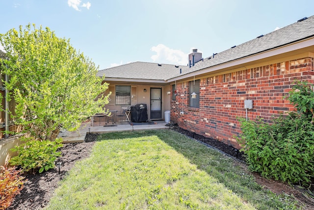 rear view of property with a lawn, brick siding, a patio area, and a chimney