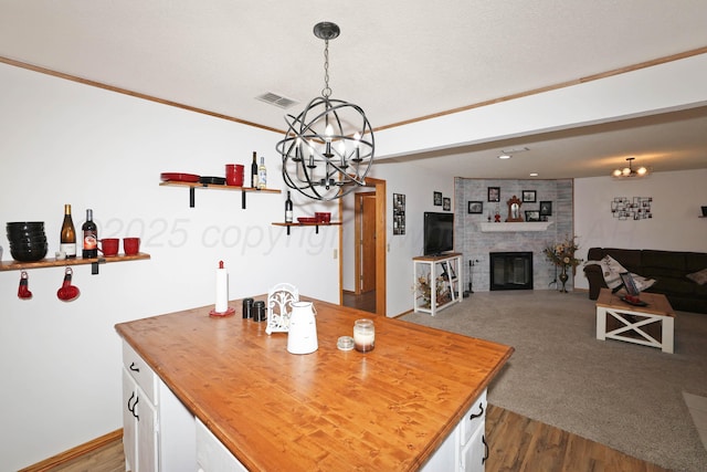 kitchen with a chandelier, wood counters, white cabinetry, a fireplace, and dark wood-style floors