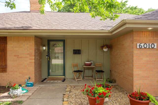 6010 Calumet Rd, Amarillo, TX 79106 - entrance to property featuring a shingled roof, board and batten siding, brick siding, and a chimney