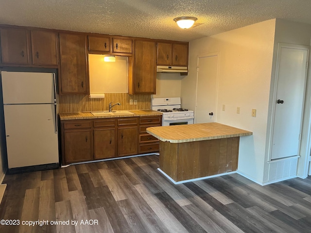 kitchen featuring dark wood-type flooring, white appliances, sink, and kitchen peninsula