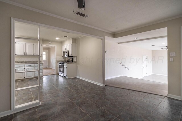 spare room with dark tile patterned floors, ceiling fan, and crown molding