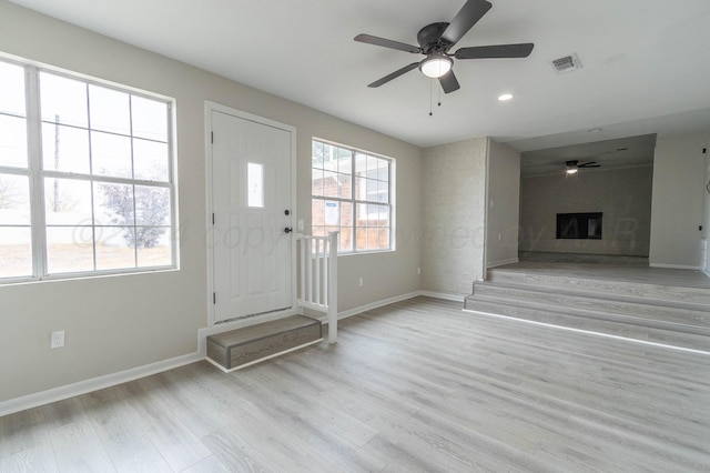 entryway with ceiling fan, light wood-type flooring, and a fireplace