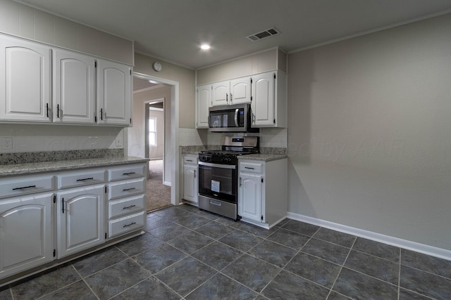 kitchen with stainless steel appliances, white cabinetry, and dark tile patterned floors