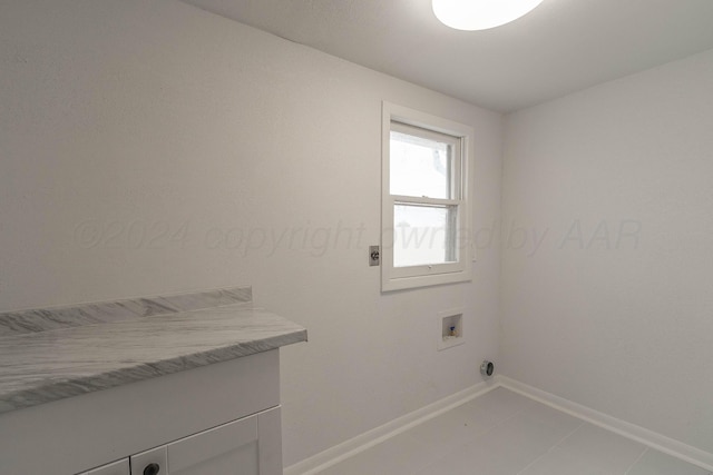 laundry room with hookup for an electric dryer, hookup for a washing machine, tile patterned floors, and cabinets