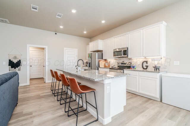 1706 Morningside Ave, Amarillo, TX 79118 - kitchen with stainless steel appliances, backsplash, light wood-style flooring, white cabinetry, and recessed lighting