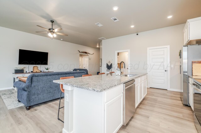 1706 Morningside Ave, Amarillo, TX 79118 - kitchen with appliances with stainless steel finishes, light wood-type flooring, a ceiling fan, a kitchen island with sink, and white cabinets