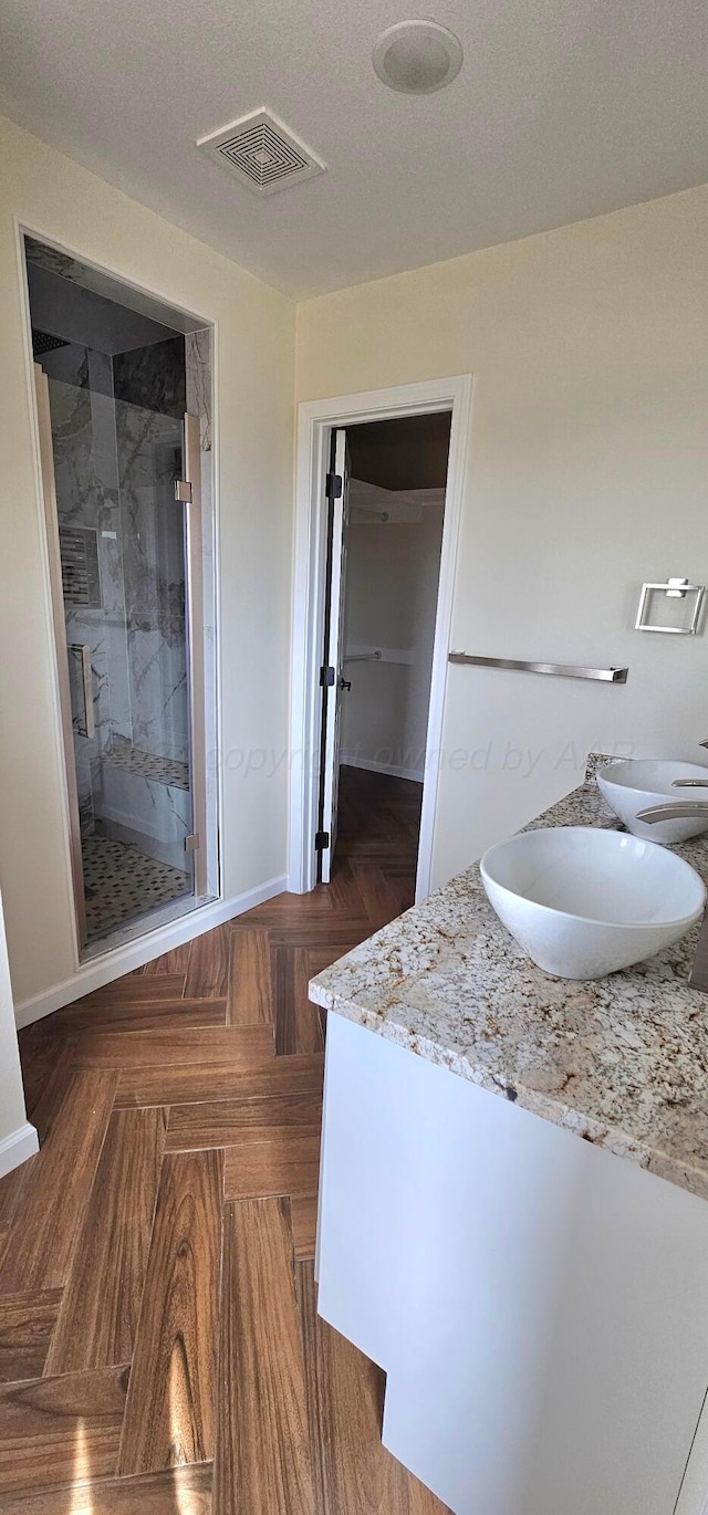 bathroom featuring an enclosed shower, vanity, and a textured ceiling