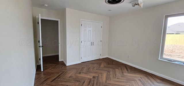 unfurnished bedroom featuring a closet and dark parquet flooring