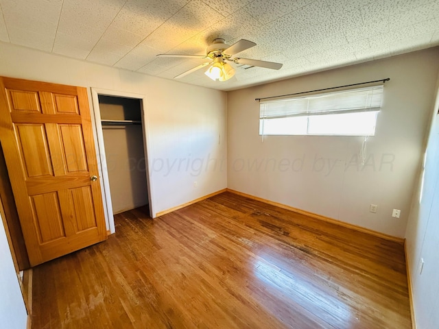 unfurnished bedroom with ceiling fan, a closet, baseboards, and wood finished floors