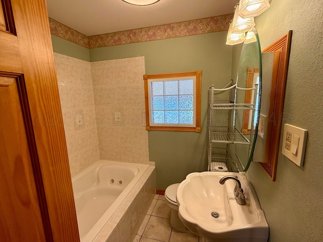 full bathroom featuring tile patterned floors, a tub with jets, toilet, and a sink