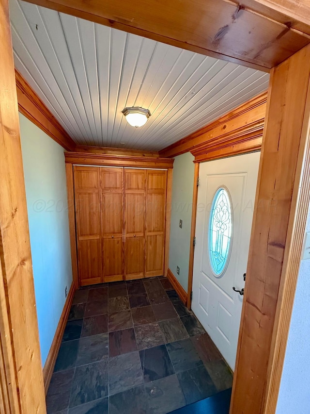 entryway with stone tile flooring, wood ceiling, and baseboards