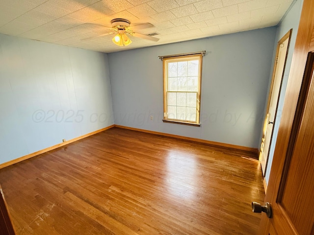 spare room featuring a ceiling fan, wood finished floors, visible vents, and baseboards