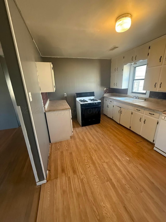 kitchen with white cabinetry, range with gas stovetop, and light wood-type flooring