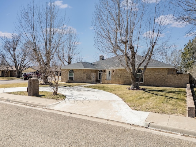 ranch-style home featuring brick siding, concrete driveway, and a front lawn