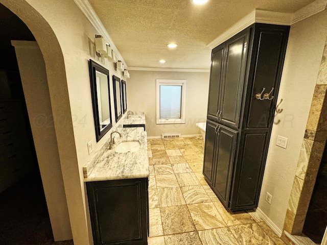 interior space with a textured ceiling, sink, light stone counters, and crown molding