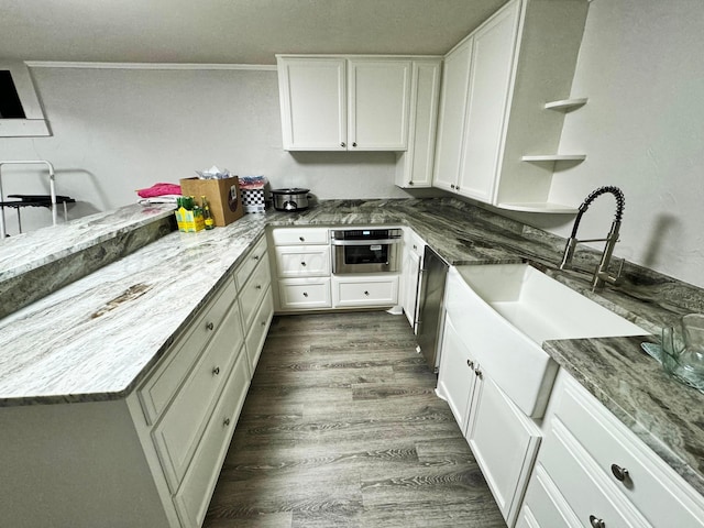 kitchen featuring stone countertops, appliances with stainless steel finishes, ornamental molding, white cabinets, and dark wood-type flooring