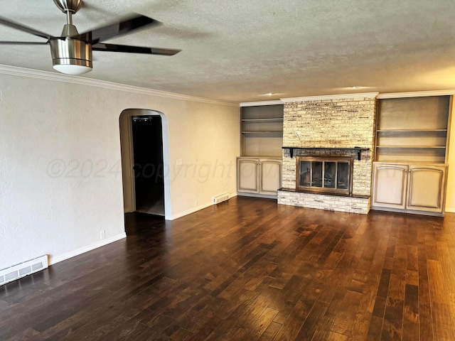 unfurnished living room featuring built in shelves, a brick fireplace, dark hardwood / wood-style flooring, and a textured ceiling