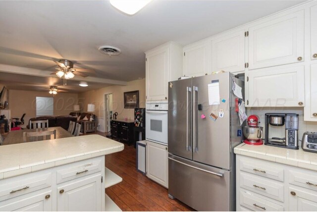 6102 Calumet Rd, Amarillo, TX 79106 - kitchen with freestanding refrigerator, oven, ceiling fan, white cabinets, and tile countertops
