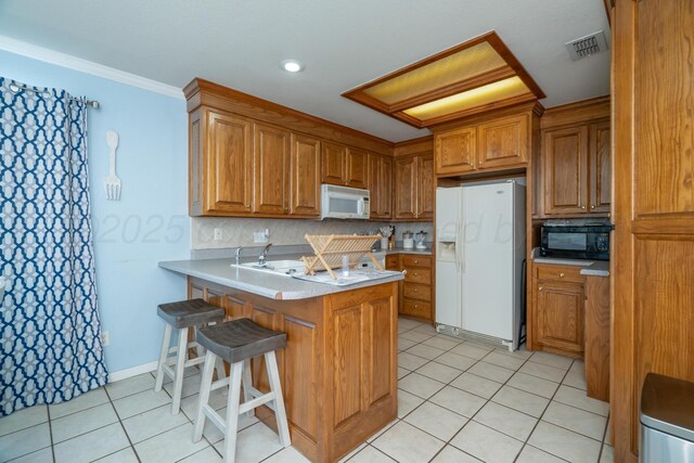 8301 San Antonio Dr, Amarillo, TX 79118 - kitchen featuring white appliances, brown cabinetry, a peninsula, and light tile patterned flooring