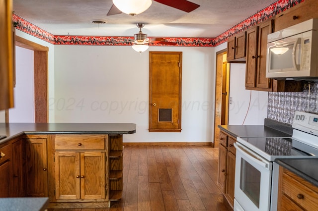 kitchen with dark wood-type flooring, kitchen peninsula, white appliances, and ceiling fan